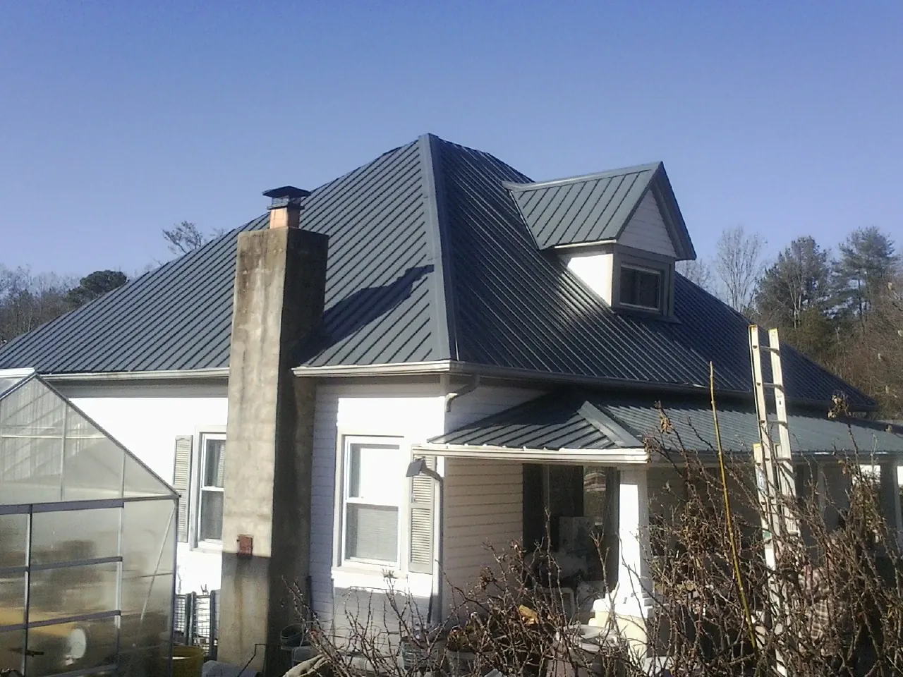 Dark blue standing seam metal roof on a white farmhouse with dormer — Slate & Tile Roof Repair by Roofing Brothers in Southbridge