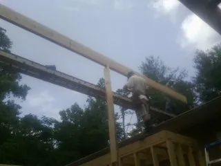 Carpenter setting a ridge beam over a new addition frame — Ice Dam Removal by Roofing Brothers in Southbridge