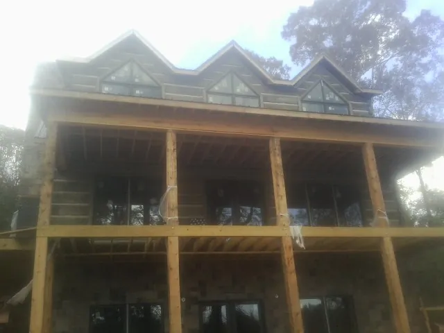 Dormers and porch framing on a large log home under construction — Roof Coating work by our crew in Southbridge