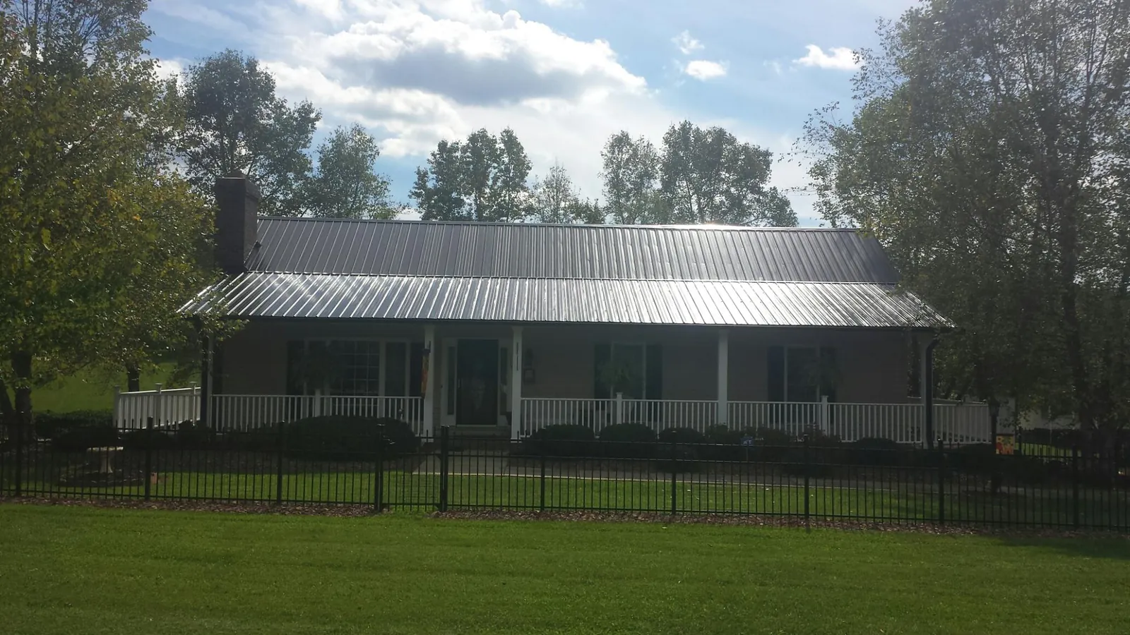 Gray metal roof on a brick ranch with a full width front porch — Gutter Guard Installation work by our crew in Southbridge